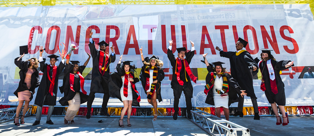 UMD graduates jumping in regalia at commencement